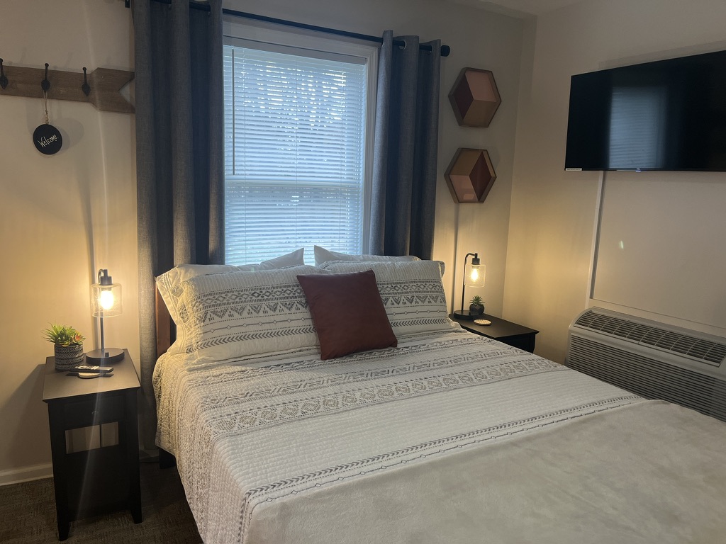 Cozy bedroom with queen bed, warm lamps, and accent decor