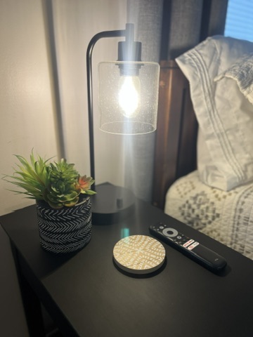 Close-up of bedside lamp, succulent, and TV remote