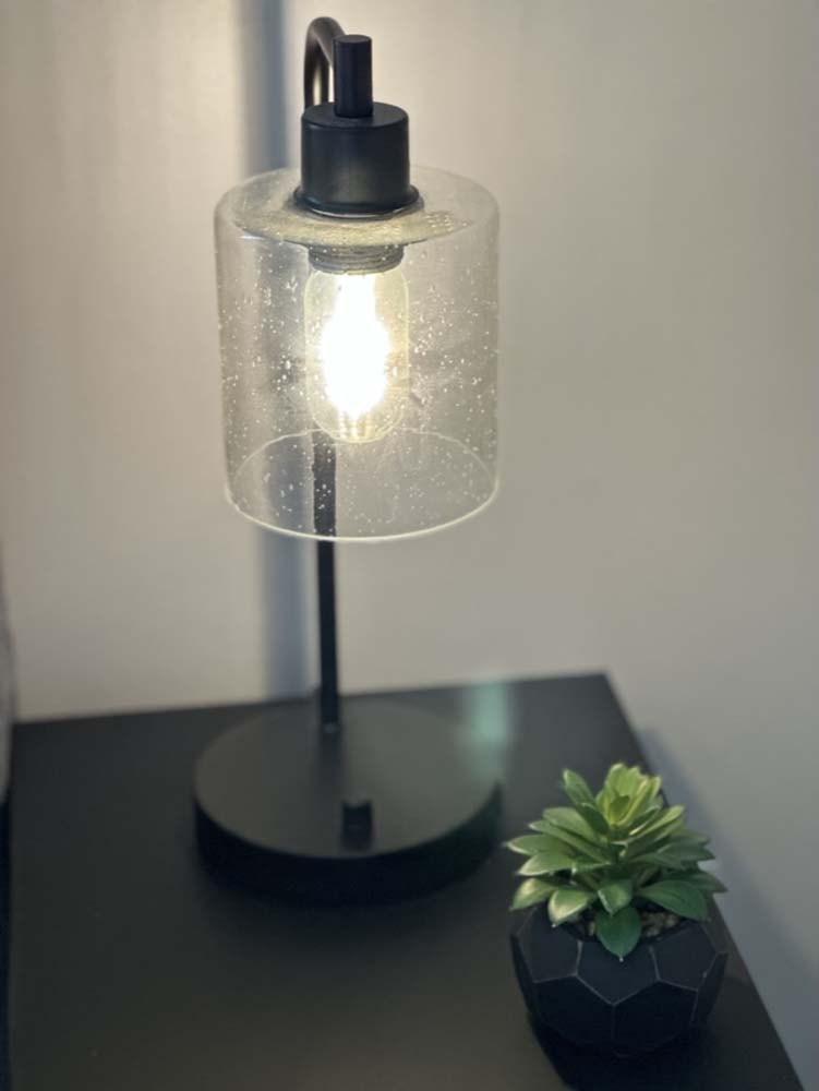 Glass-shade bedside lamp glowing next to a small succulent
