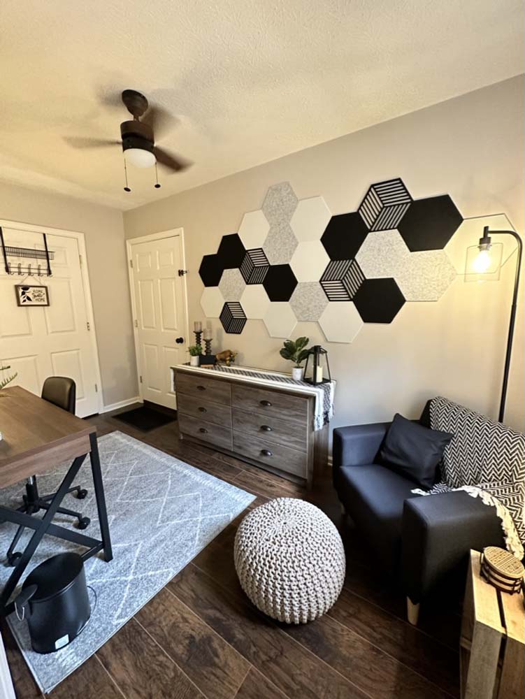Office room with hexagon accent wall, dresser, and sofa