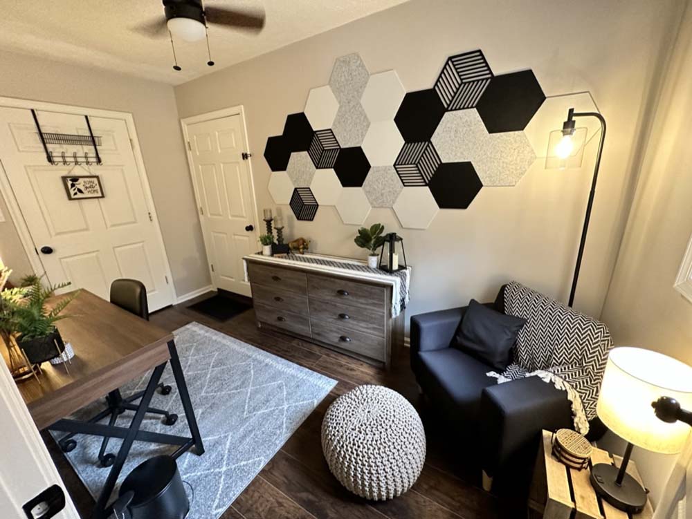 Second room with desk, sofa, and hexagon wall art