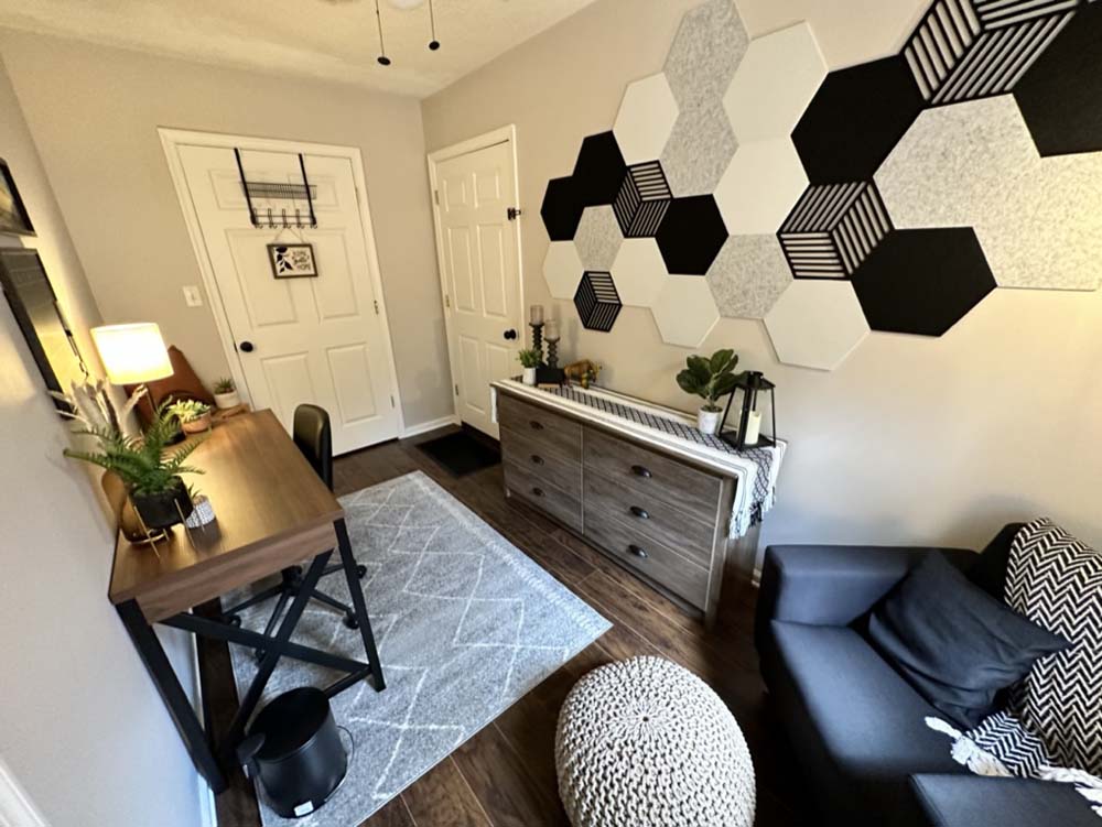 Wide view of office room with desk, dresser, and hexagon wall