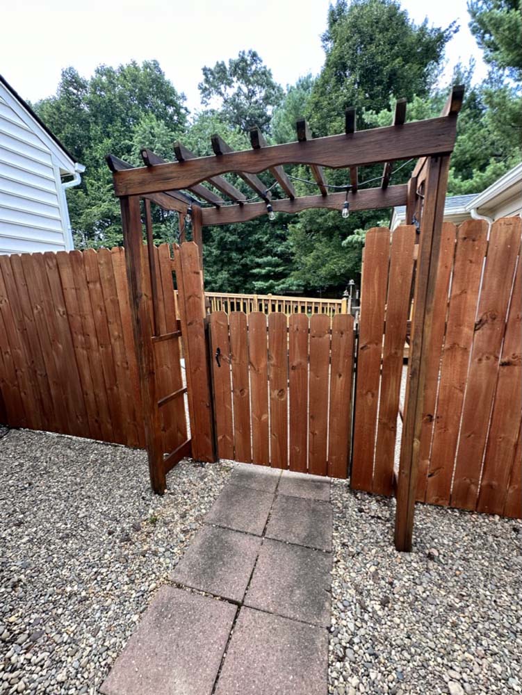 Wooden pergola gate framed by trees from inside the courtyard
