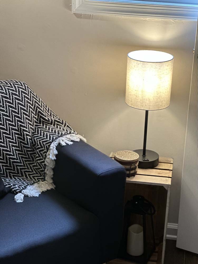 Navy sofa corner with woven throw and warm table lamp