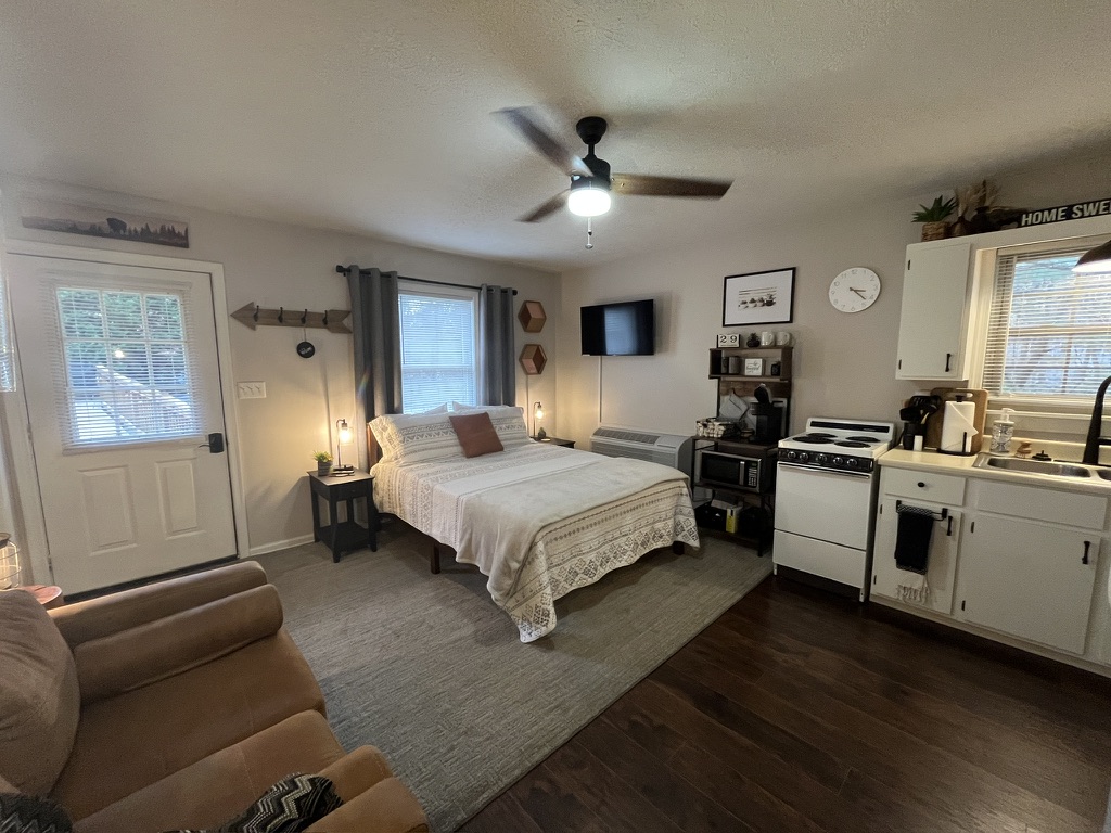 Wide view of the studio apartment with bed, kitchen, and entry
