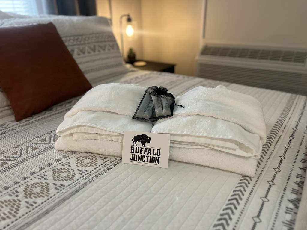 Folded welcome towels and Buffalo Junction card on the bed